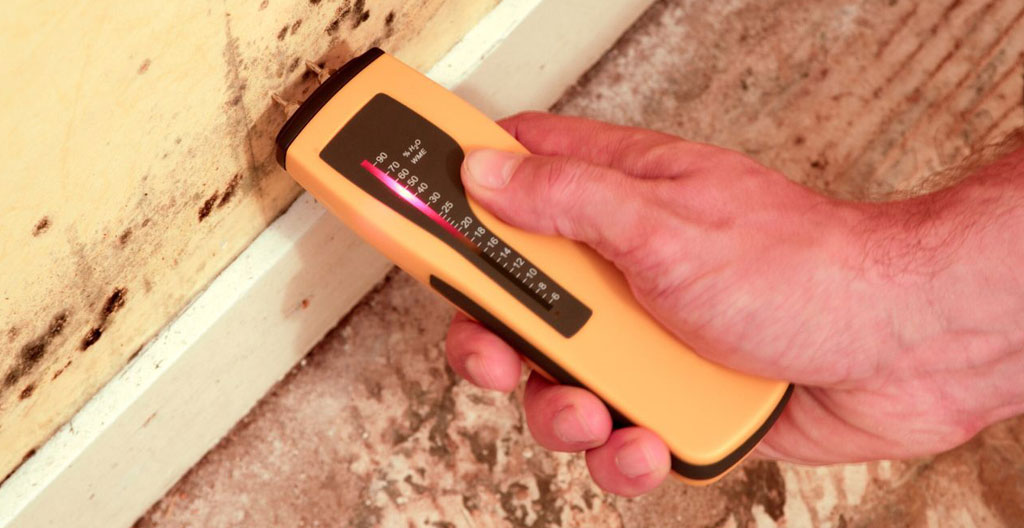 Un thermomètre ou une station météo au premier plan dans un entrepôt industriel, avec la silhouette floue d'un travailleur en arrière-plan sous un éclairage artificiel